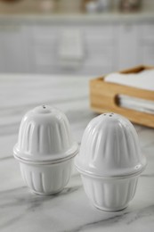 Ceramic salt and pepper shakers on white marble table in kitchen