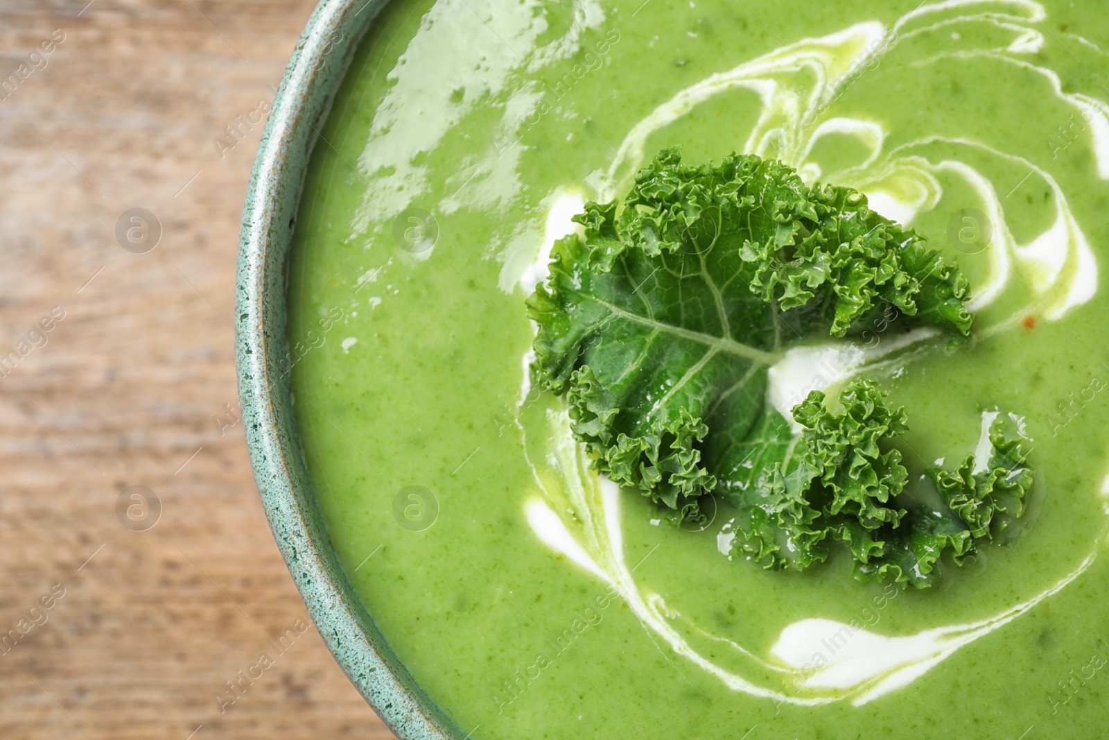 Photo of Tasty kale soup on wooden table, top view
