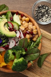 Delicious vegan bowl with broccoli, avocados and chickpeas on wooden table, flat lay