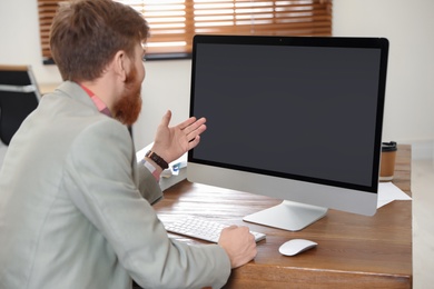 Photo of Man using video chat on computer in home office. Space for text
