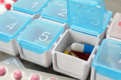 Plastic box with different pills on table, closeup