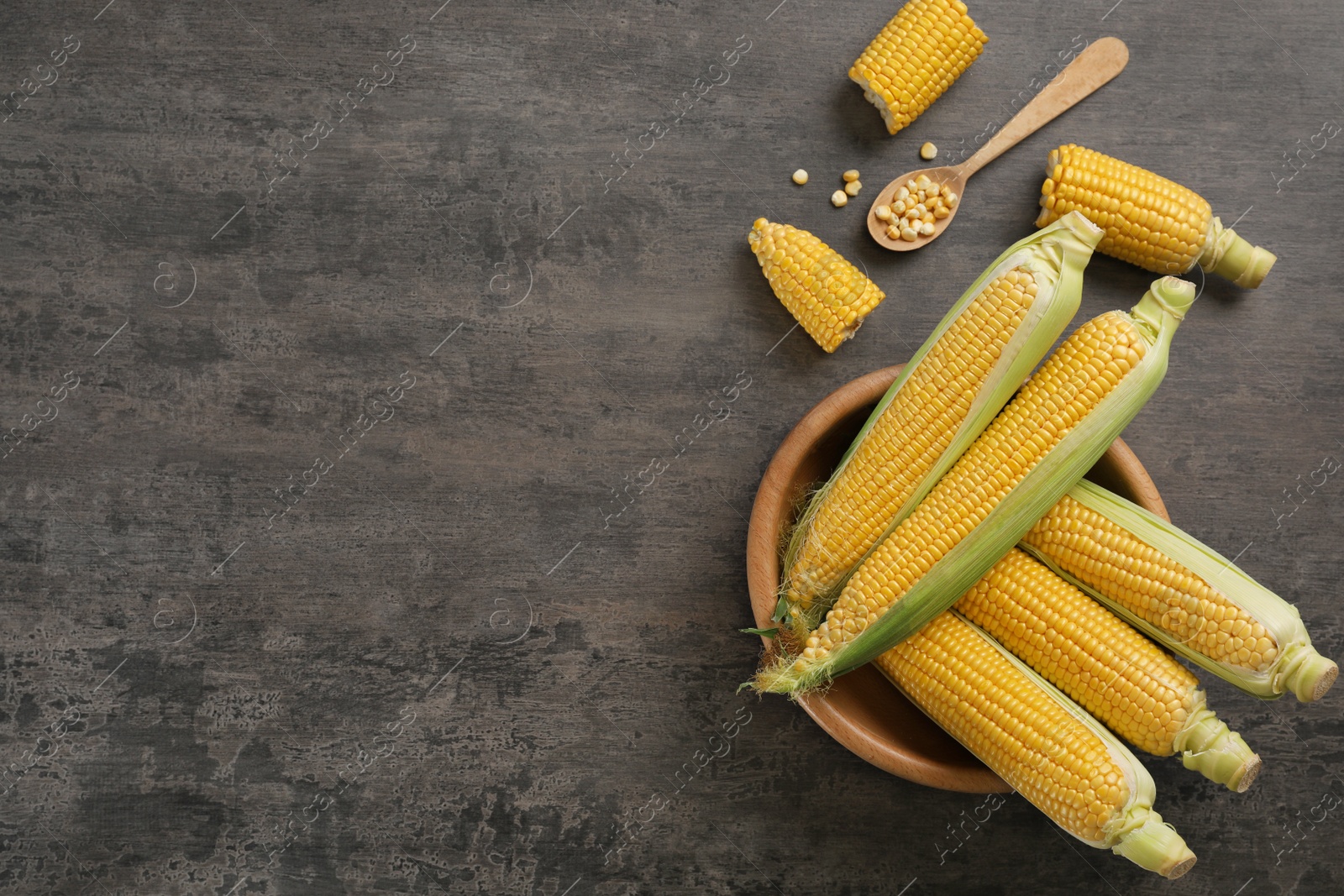 Photo of Bowl with tasty sweet corn cobs on table, top view