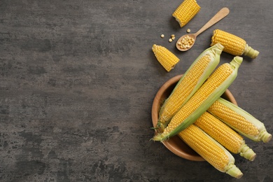 Photo of Bowl with tasty sweet corn cobs on table, top view