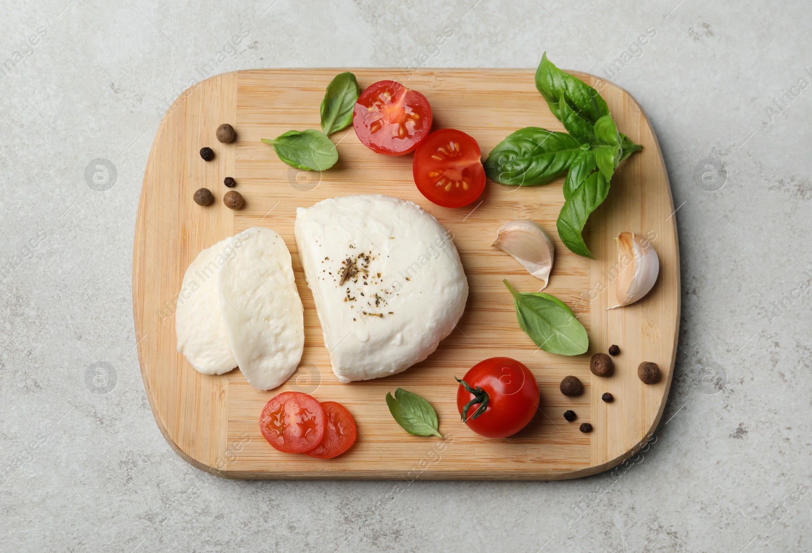 Photo of Delicious mozzarella with tomatoes and basil leaves on light gray table, top view