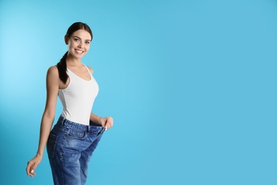 Photo of Attractive young woman with slim body wearing her old big jeans on color background. Space for text