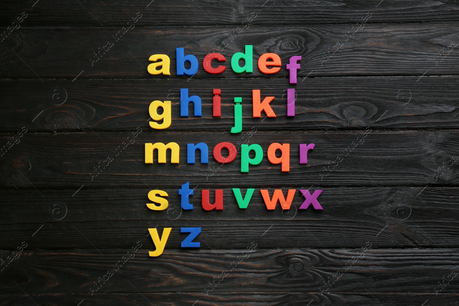 Photo of Colorful magnetic letters on black wooden background, flat lay. Alphabetical order