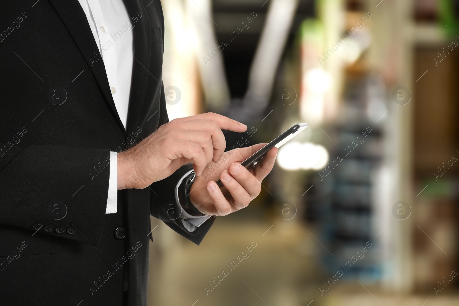 Image of Wholesale trading. Man using WMS app on smartphone at warehouse, closeup 