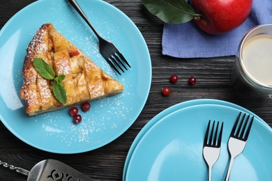 Slice of traditional apple pie served on black wooden table, flat lay