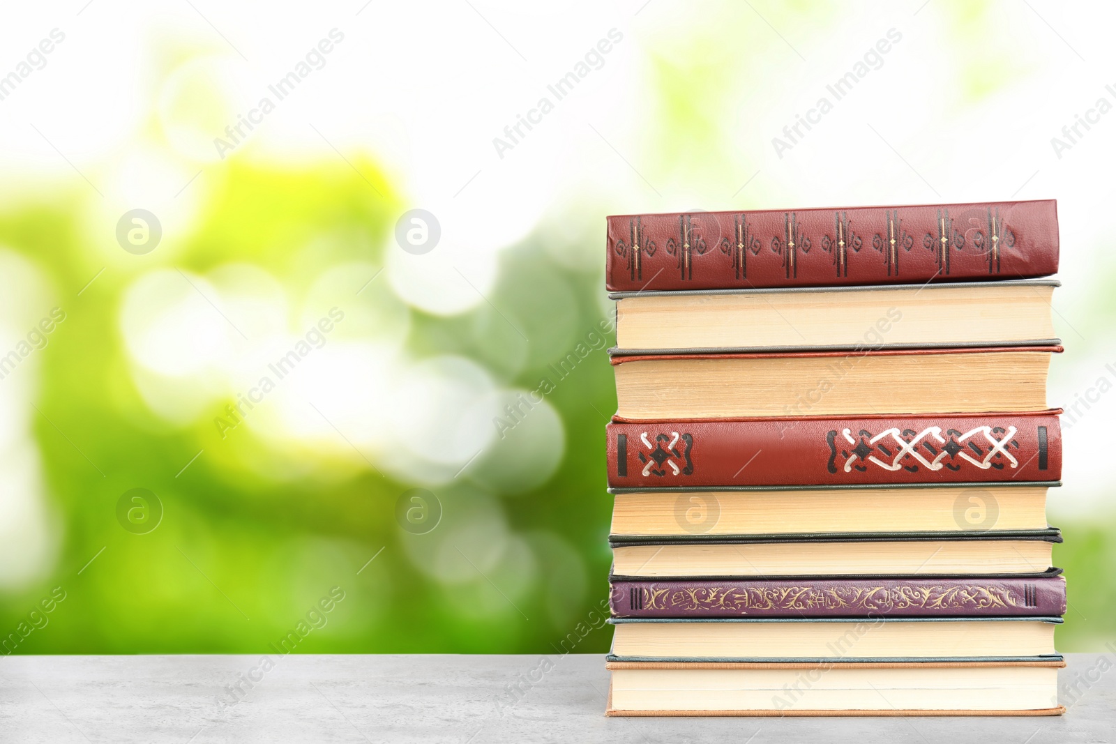 Image of Collection of different books on table against blurred green background, space for text