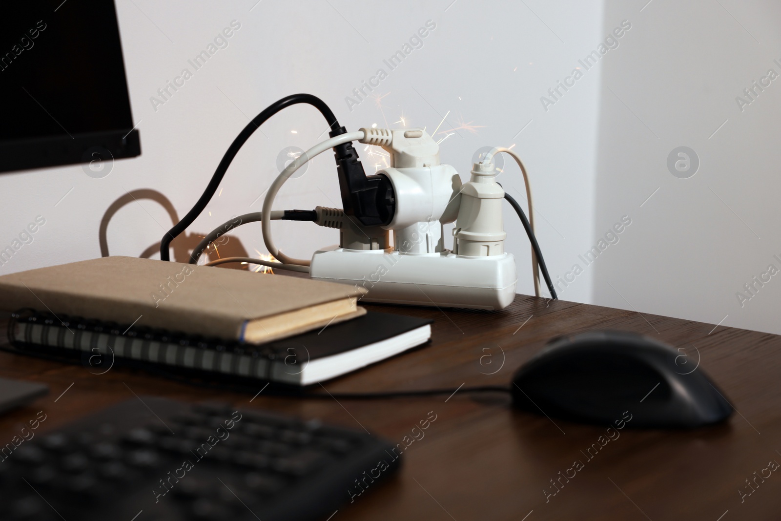 Photo of Inflamed plug in power strip indoors on wooden table. Electrical short circuit