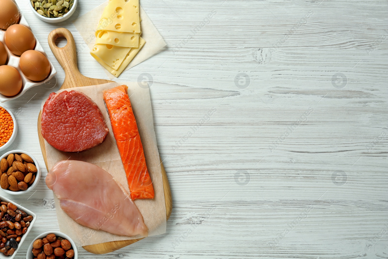 Photo of Different fresh products on white wooden table, flat lay and space for text. Sources of essential amino acids