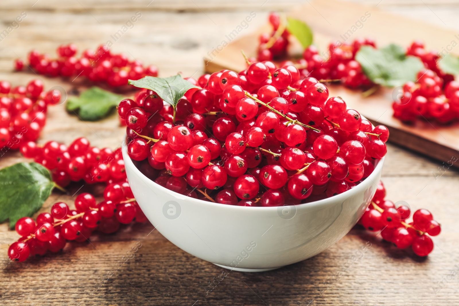 Photo of Delicious red currants in bowl on wooden table