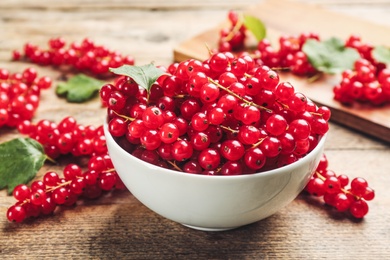 Photo of Delicious red currants in bowl on wooden table