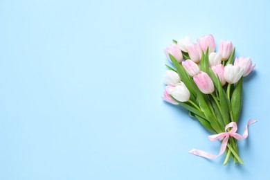 Photo of Beautiful pink spring tulips on light blue background, top view. Space for text
