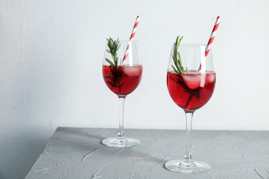 Photo of Tasty refreshing cranberry cocktail with rosemary on table