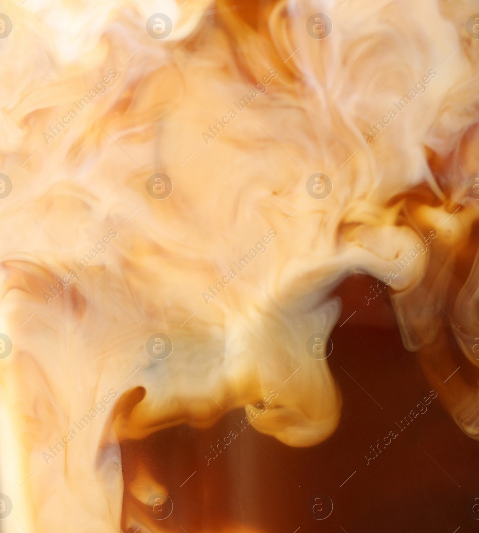 Photo of Glass of coffee with milk and ice cubes on blurred background, closeup