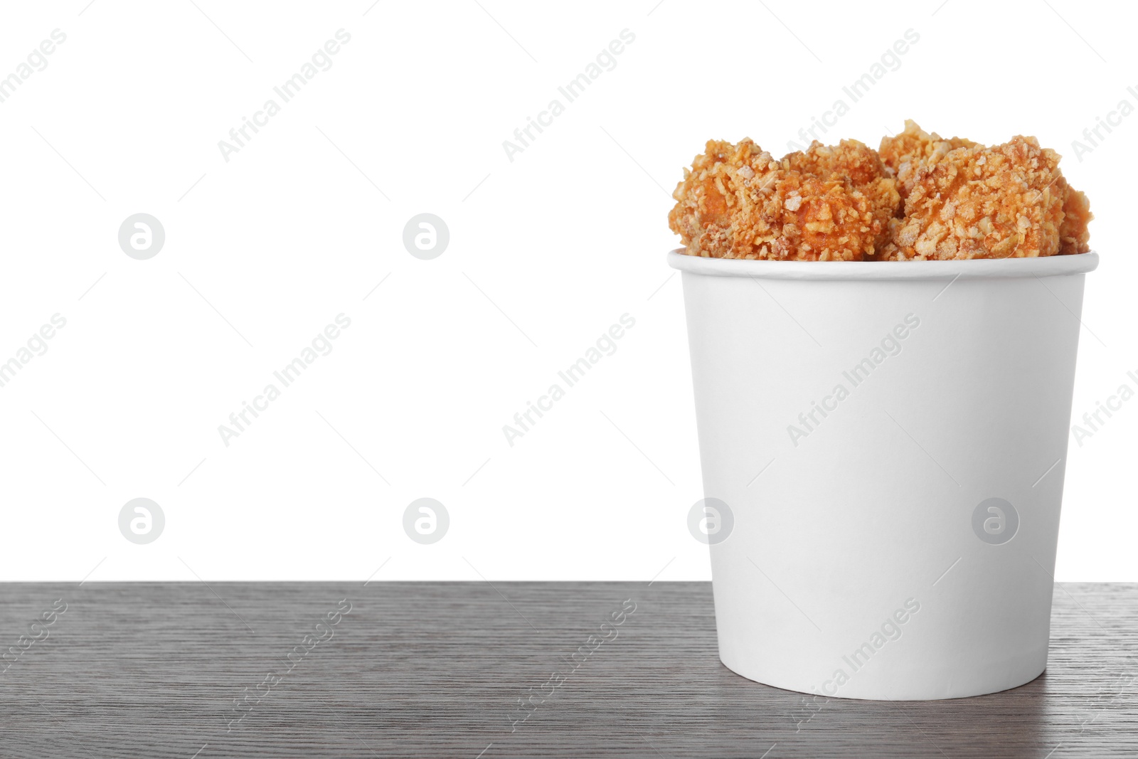 Photo of Bucket with yummy nuggets on dark wooden table against white background, space for text