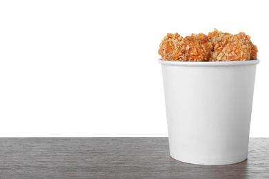 Photo of Bucket with yummy nuggets on dark wooden table against white background, space for text