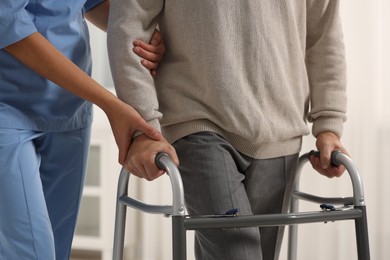 Photo of Nurse helping elderly patient with walker indoors, closeup