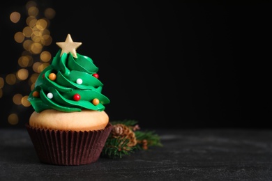 Photo of Christmas tree shaped cupcake on black table. Space for text