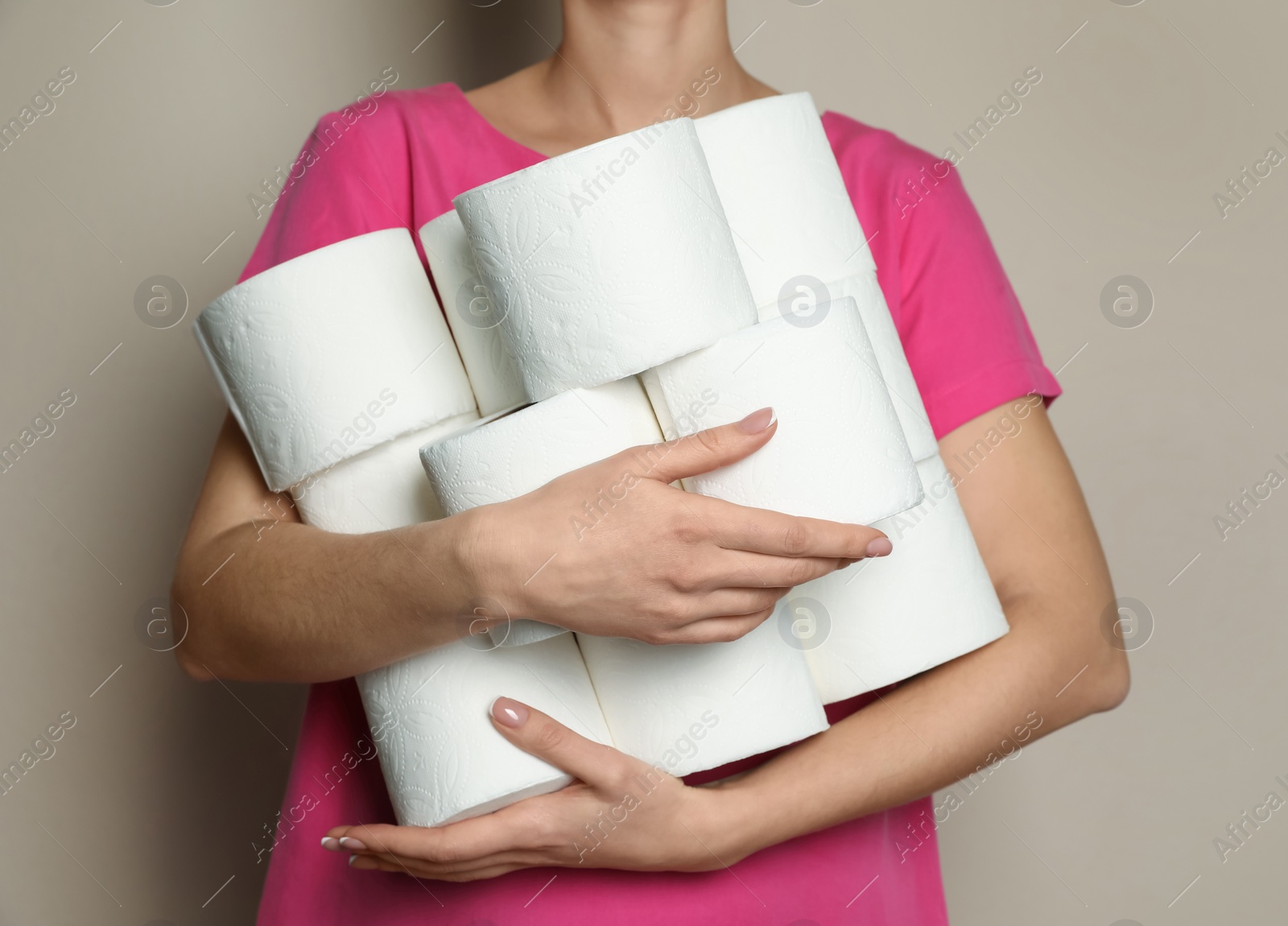 Photo of Woman with heap of toilet paper rolls on beige background, closeup