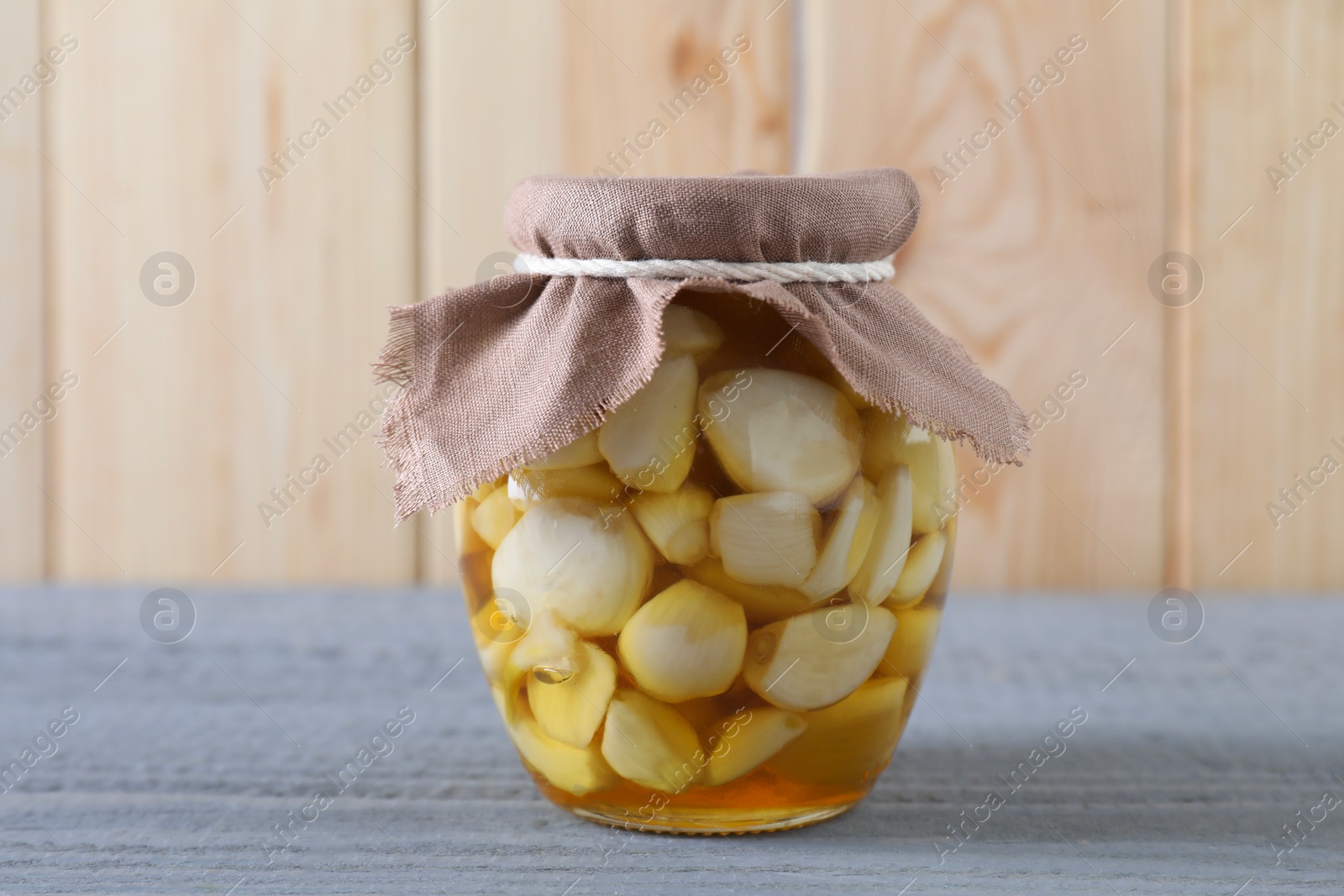 Photo of Garlic with honey in glass jar on grey wooden table