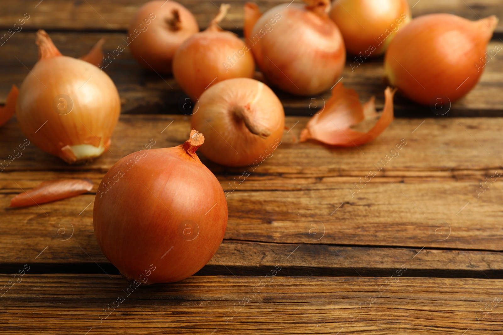 Photo of Many ripe onion bulbs on wooden table