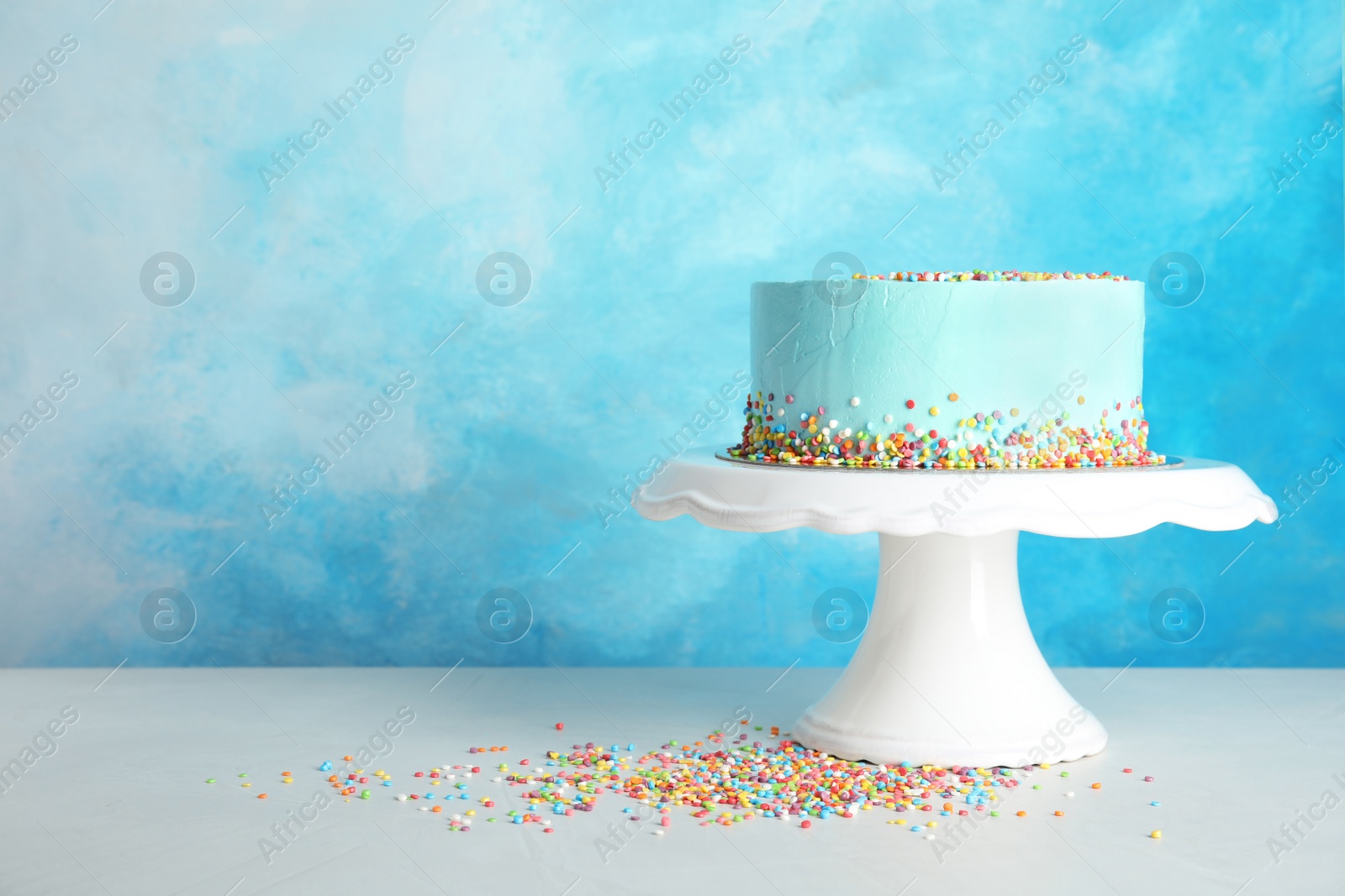 Photo of Fresh delicious birthday cake on stand against color background. Space for text