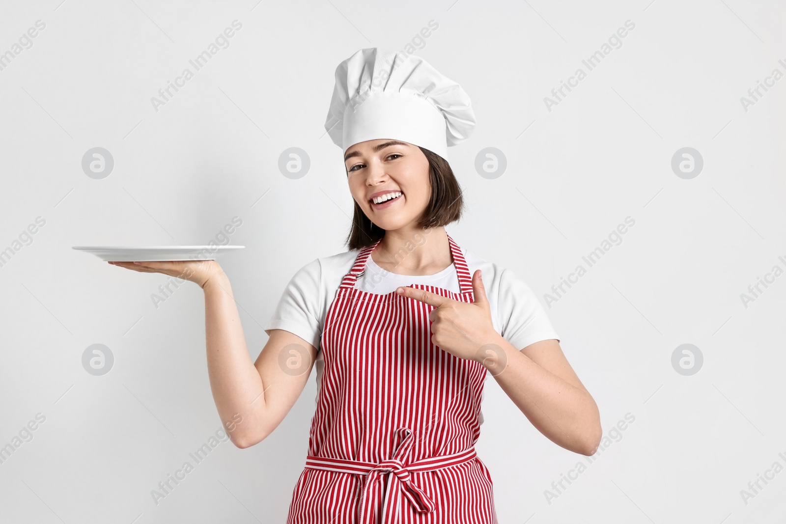 Photo of Happy confectioner with plate on light grey background