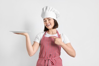 Photo of Happy confectioner with plate on light grey background