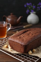 Photo of Delicious chocolate sponge cake and nuts on wooden table, closeup