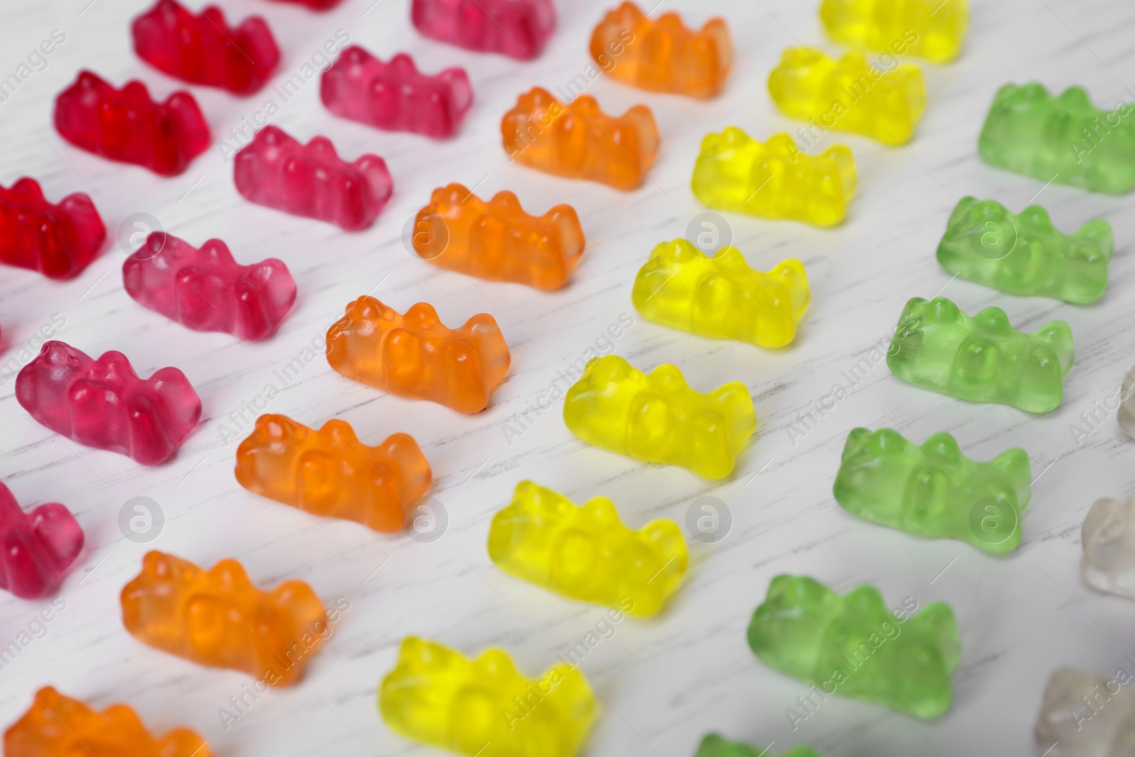 Photo of Delicious color jelly bears on white wooden table