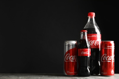 MYKOLAIV, UKRAINE - NOVEMBER 15, 2018: Bottles and cans with Coca Cola on table against black background. Space for text