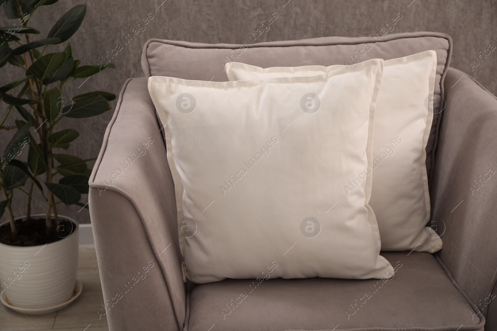 Photo of Soft pillows on grey armchair in room