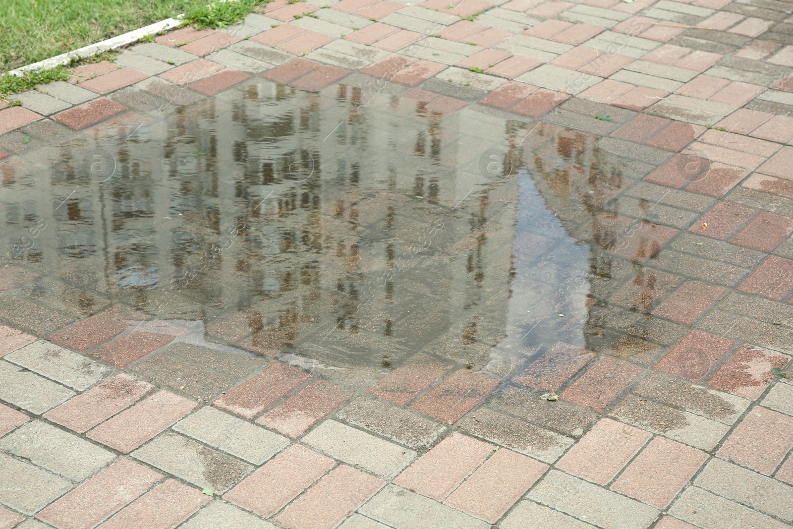 Photo of Puddle after rain on street tiles outdoors