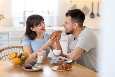 Photo of Tasty breakfast. Happy wife feeding her husband at home