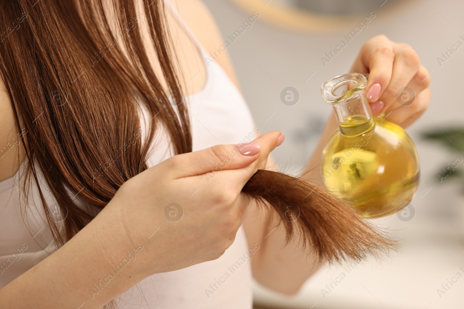 Photo of Woman applying oil hair mask at home, closeup