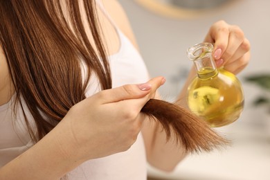 Woman applying oil hair mask at home, closeup