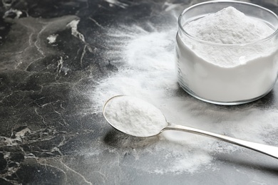 Photo of Jar and spoon with baking soda on grey background. Space for text