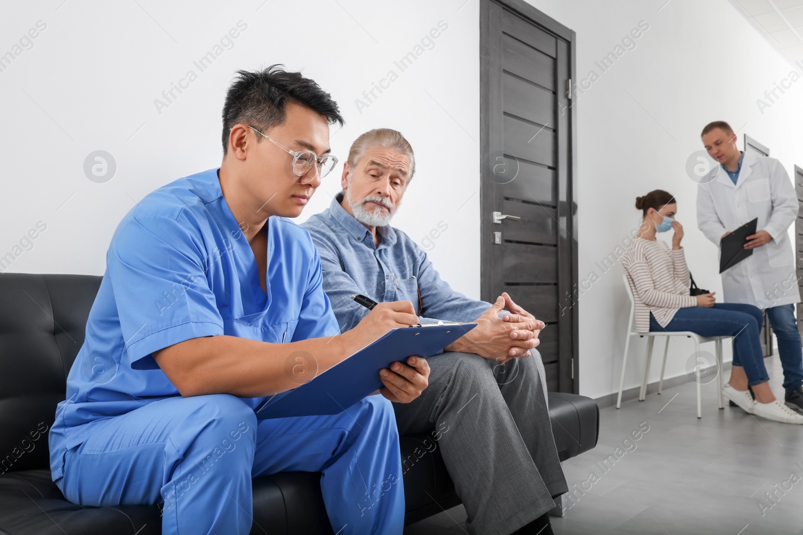 Photo of Doctor with clipboard consulting senior patient in clinic