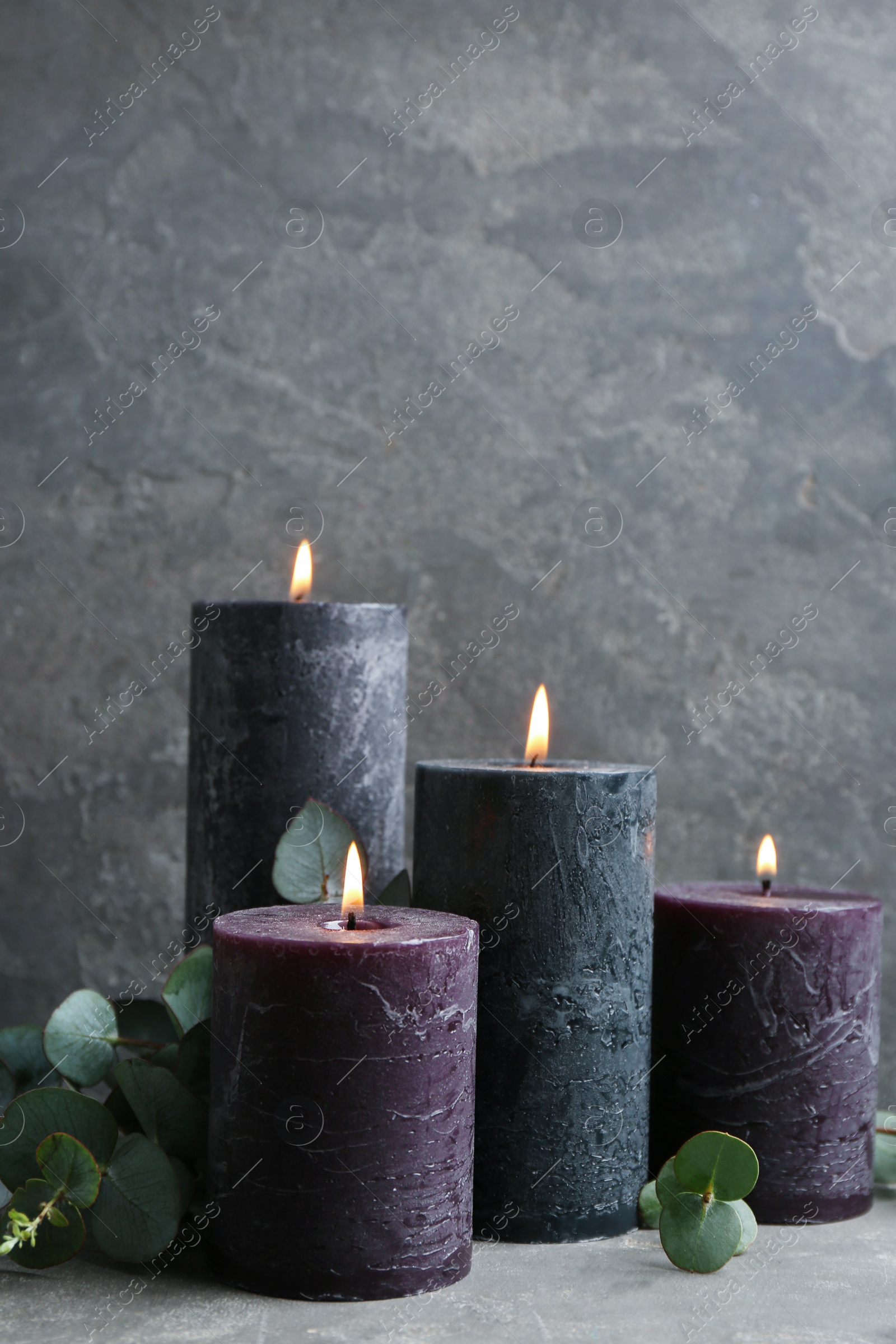 Photo of Burning candles and green branches on grey table, space for text