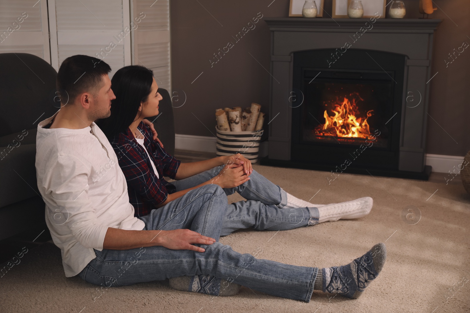 Photo of Lovely couple spending time together near fireplace at home