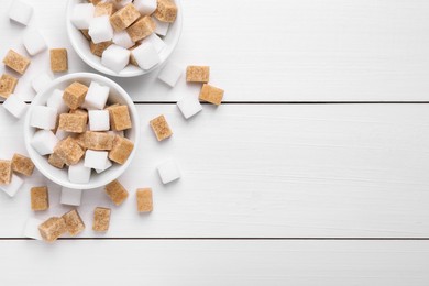 Photo of Different sugar cubes in bowls on white wooden table, flat lay. Space for text