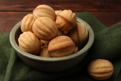 Photo of Delicious nut shaped cookies with boiled condensed milk on wooden table, closeup