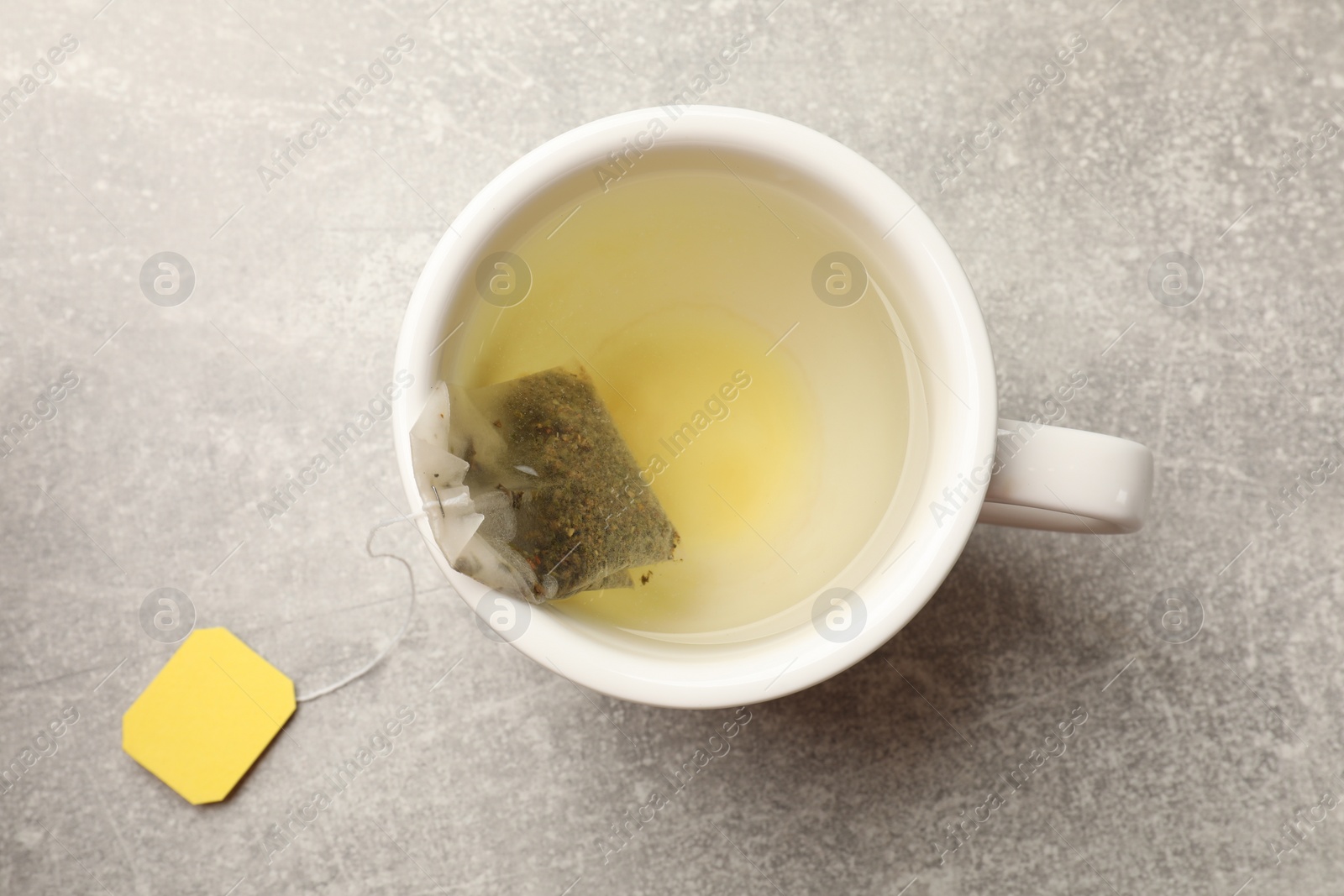 Photo of Brewing tea. Cup with tea bag on light table, top view