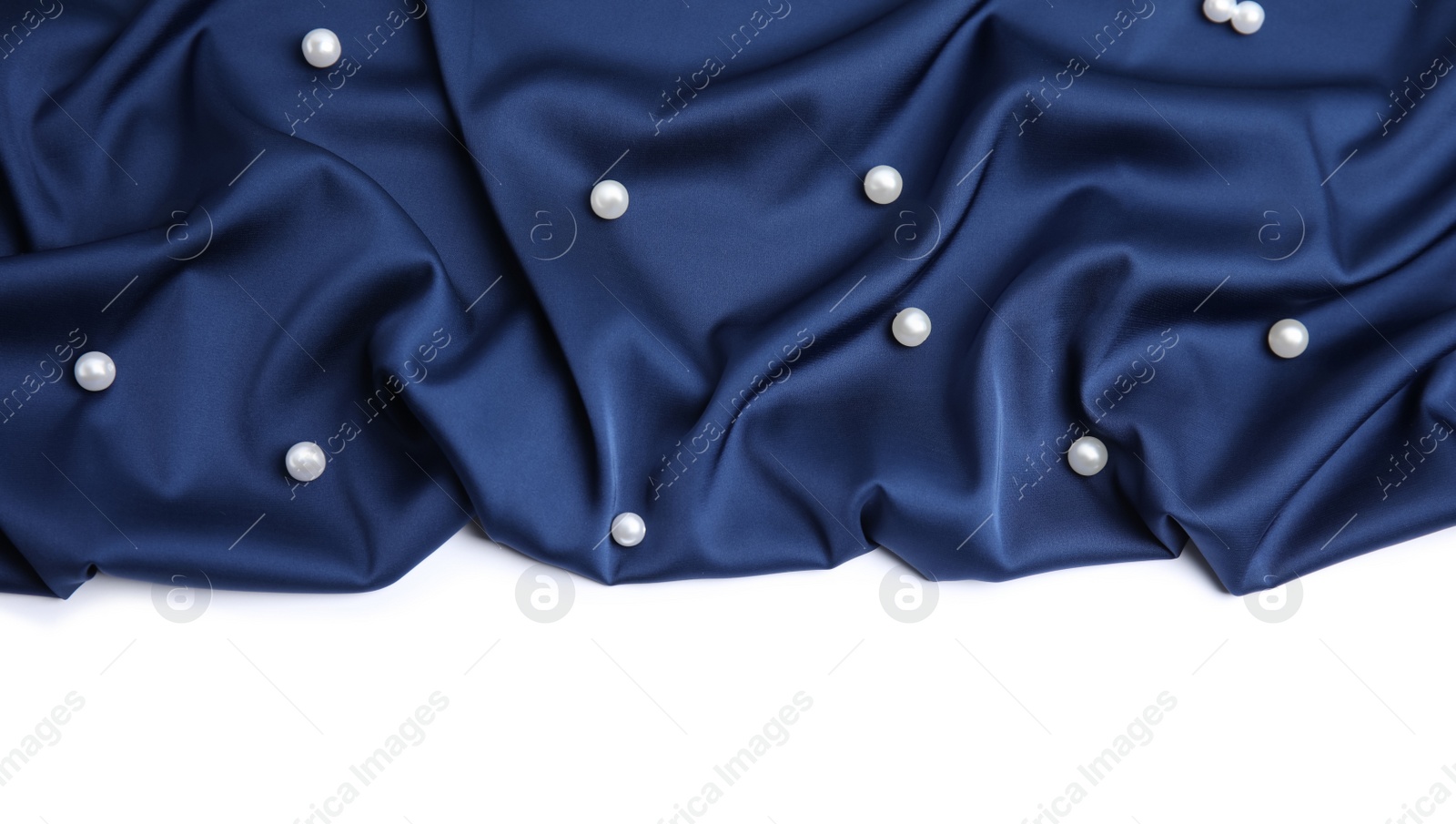Photo of Texture of delicate dark blue silk with pearls on white background, top view