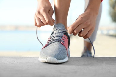 Sporty woman tying shoelaces before running outdoors