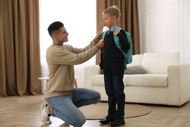 Photo of Father helping his little child get ready for school at home