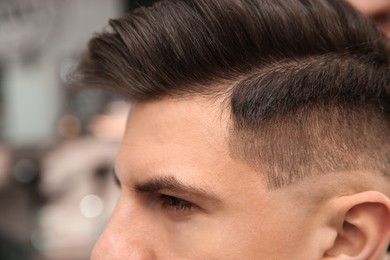Photo of Handsome man with stylish haircut in salon, closeup