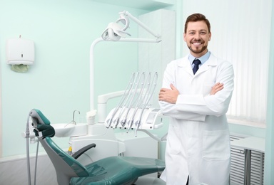 Photo of Professional male dentist in white coat at workplace. Space for text